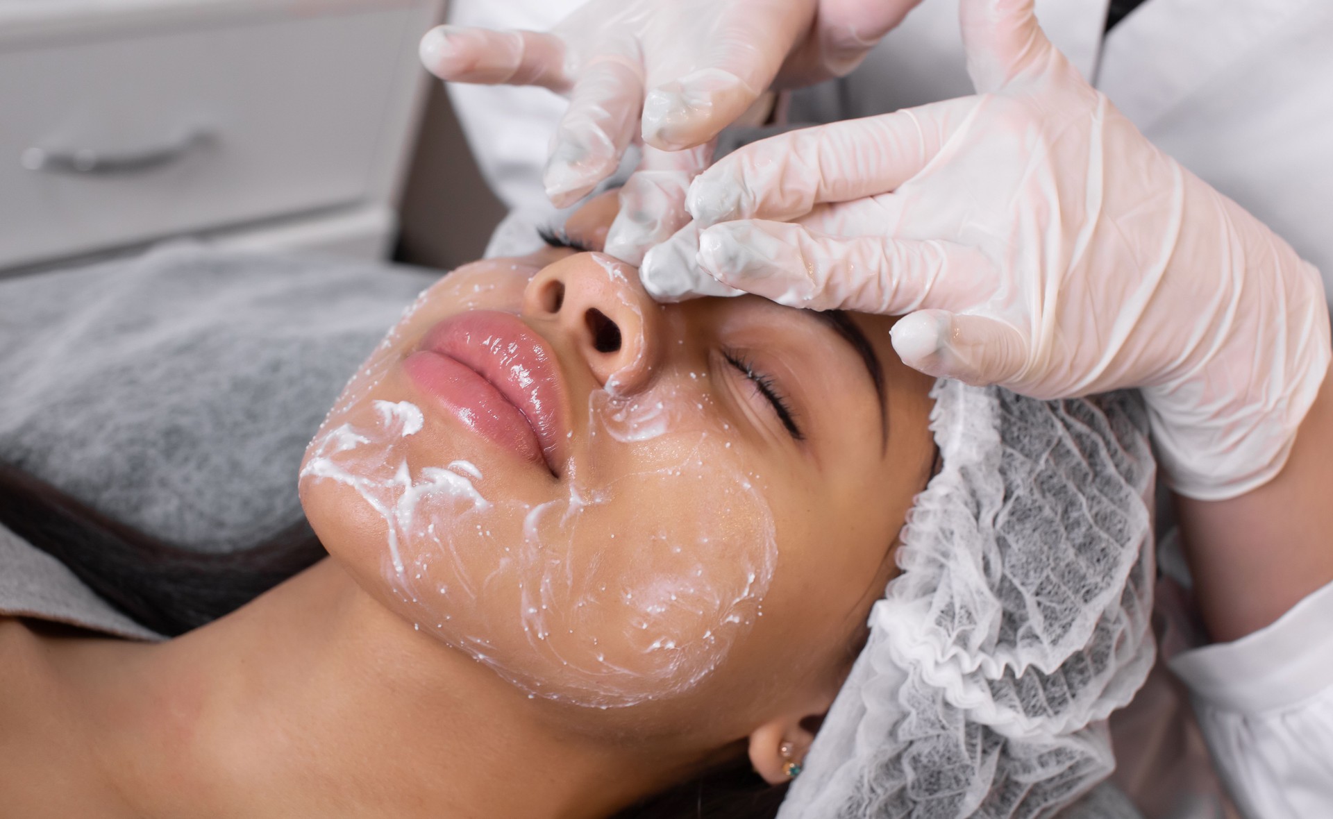 Cosmetologist applying cream essence essential vitamins into face to improve client skin. Beauty expert makes beauty treatment for patient. Health, skin care, aesthetic medicine concept.